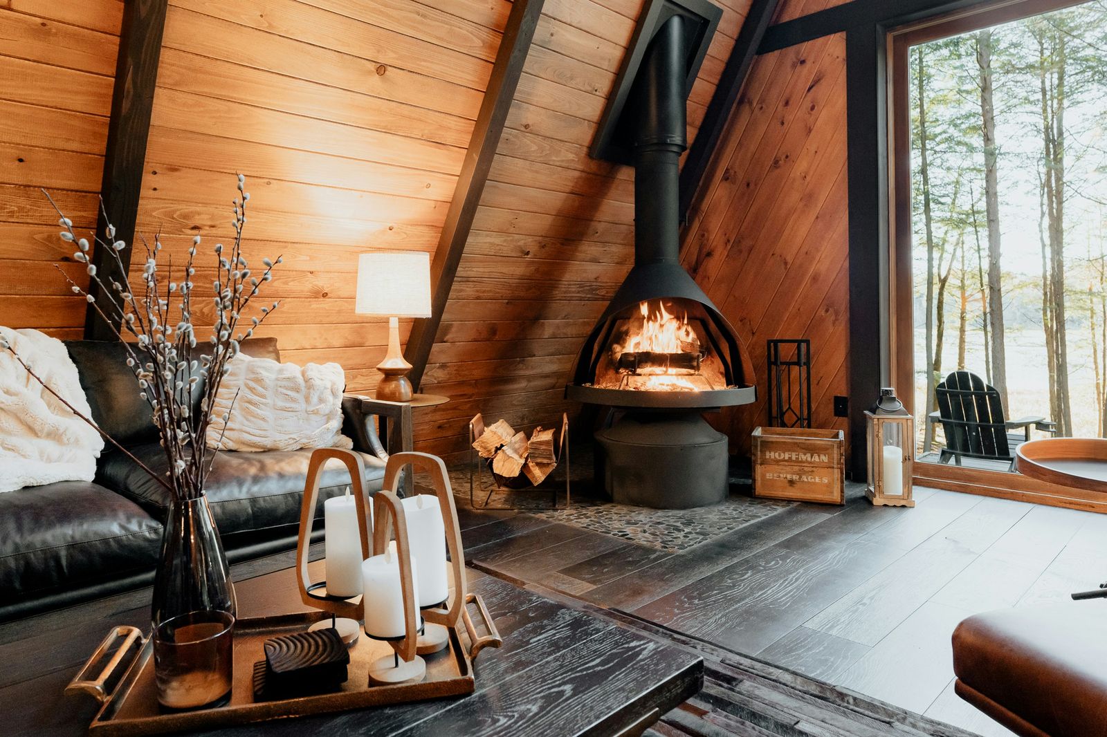 Wooden chalet interior with fireplace, candles and a forest view