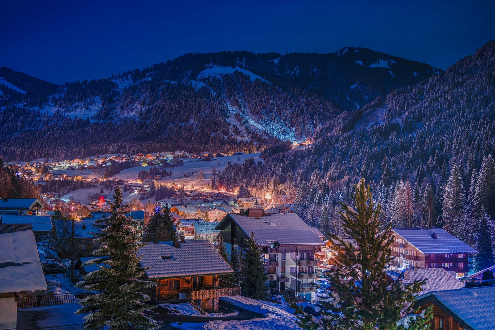Snowy ski village lit up at dusk